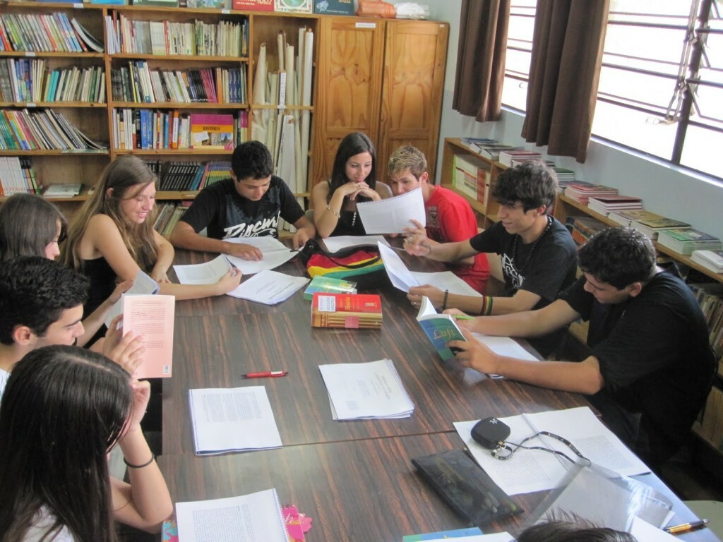 grupo de estudos: imagem de vários alunos sentados na mesa de uma biblioteca