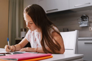 Uso da crase: imagem de uma menina escrevendo no caderno