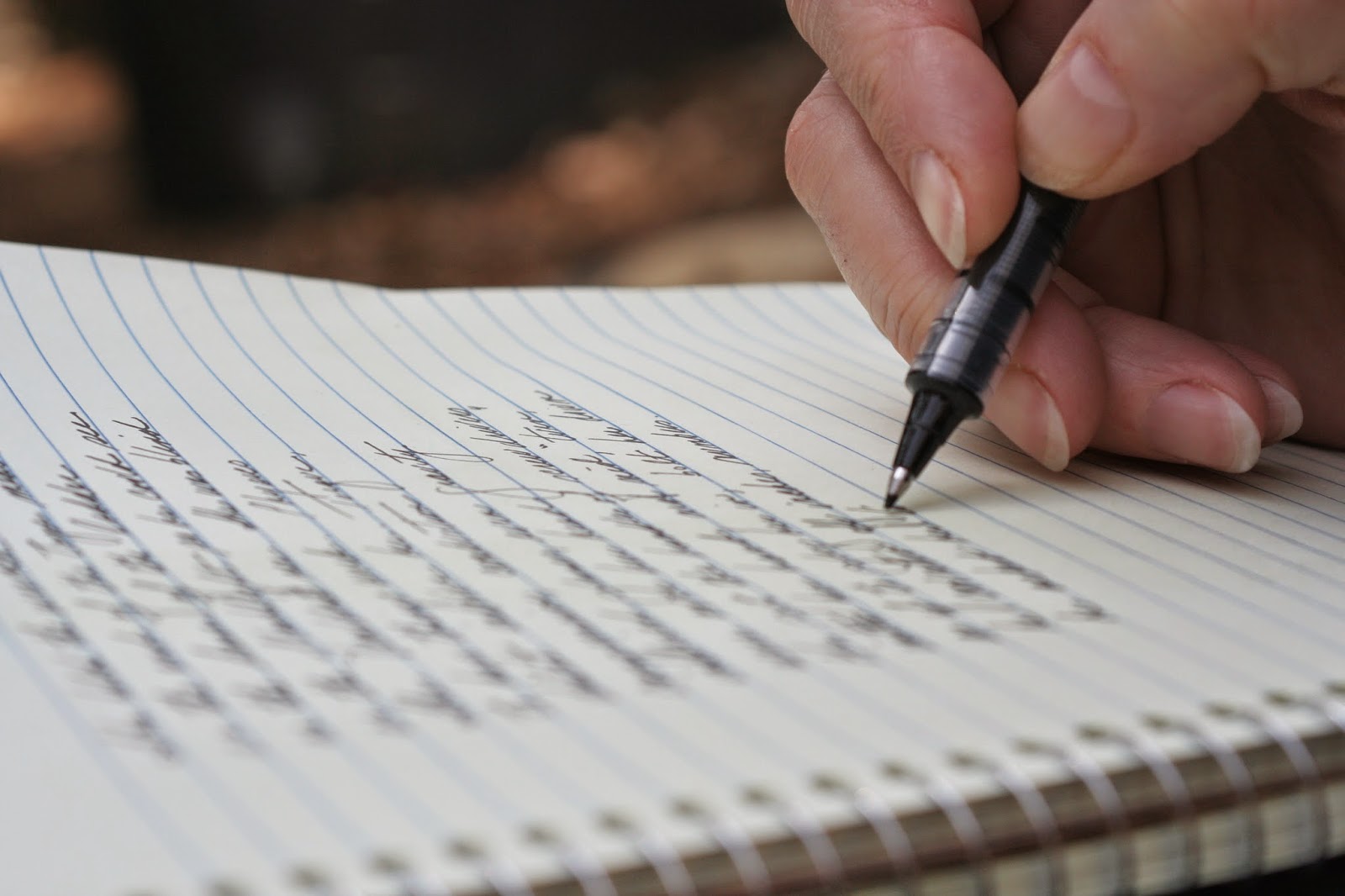 mão segurando caneta escrevendo no caderno