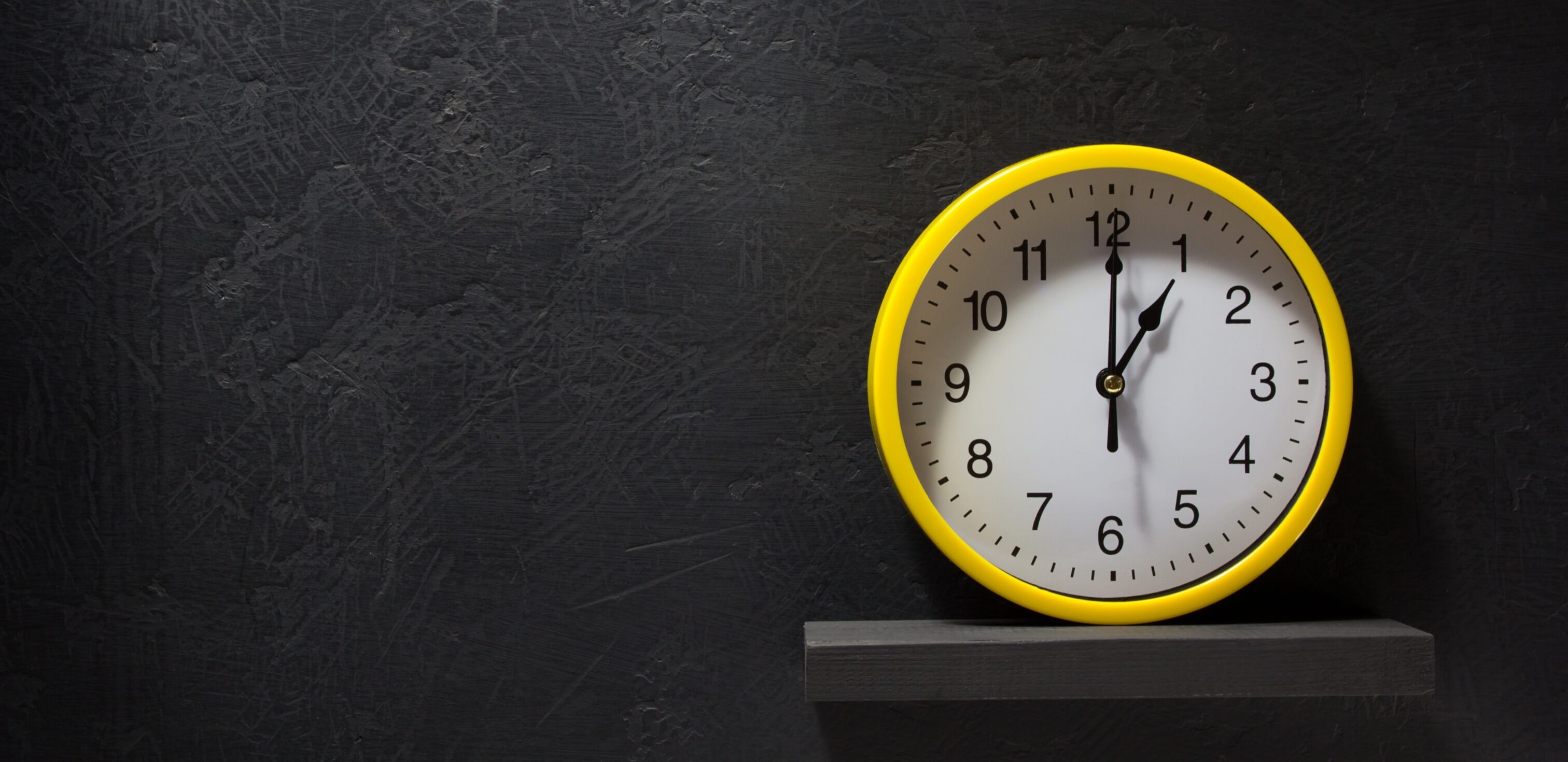 Como organizar o tempo na prova do ENEM: fotografia de um relógio sobre um quadro negro.