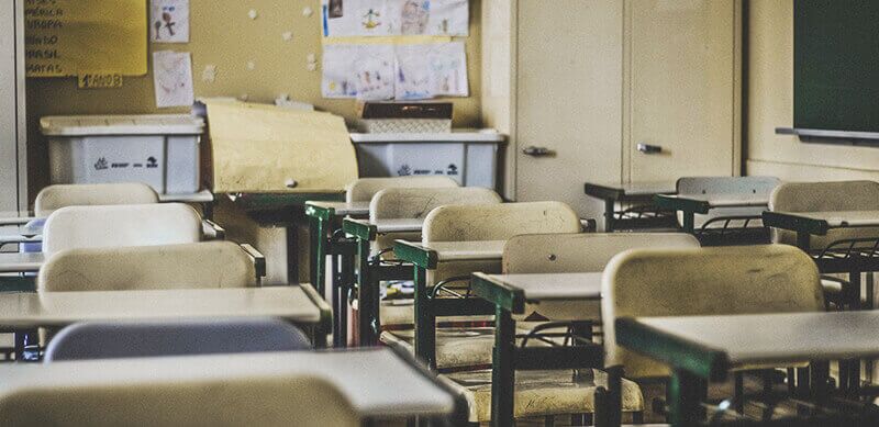Sala de aula com mesas e cadeiras.