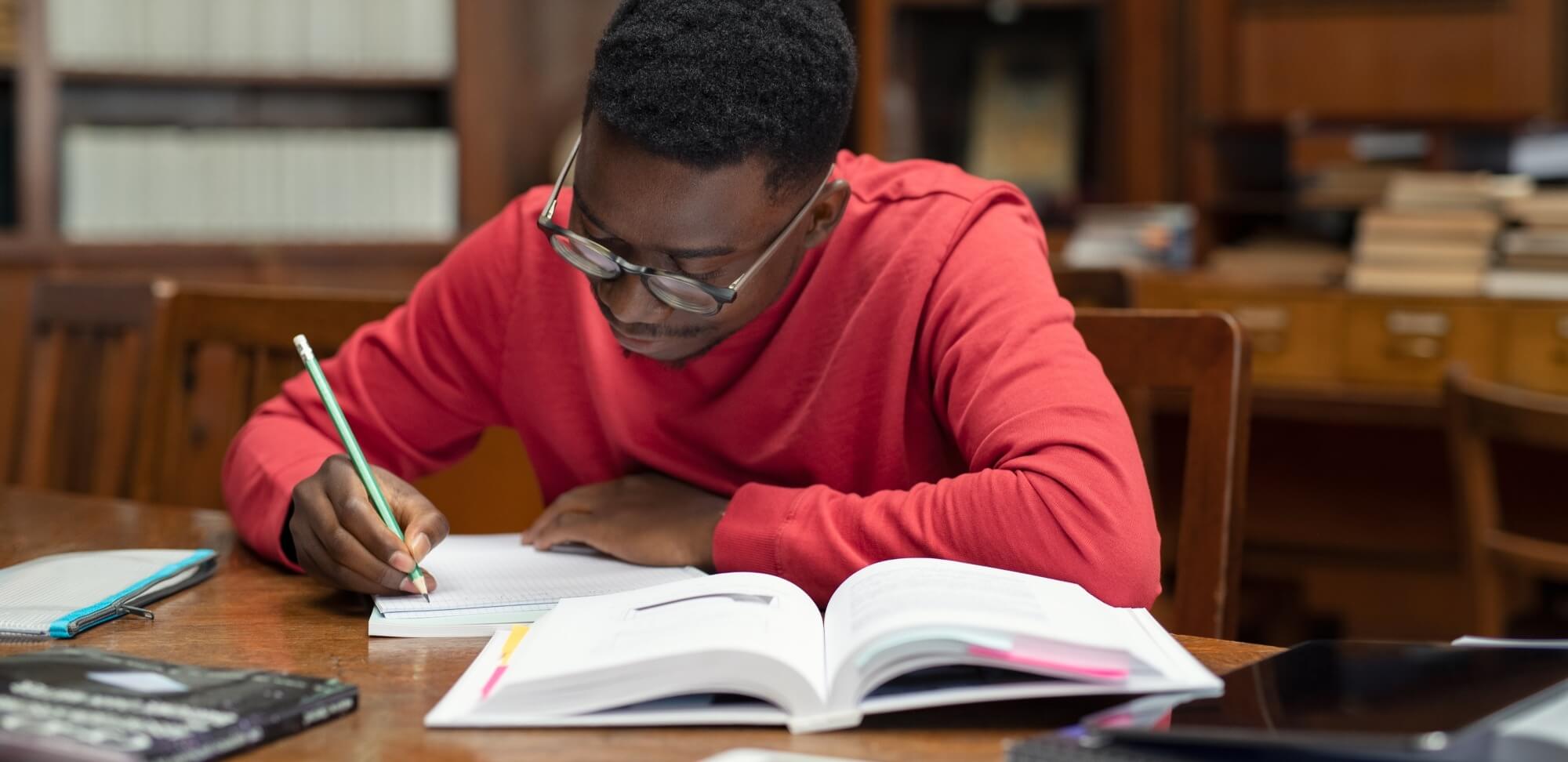 edital do enem: imagem de um estudante escrevendo em seu caderno