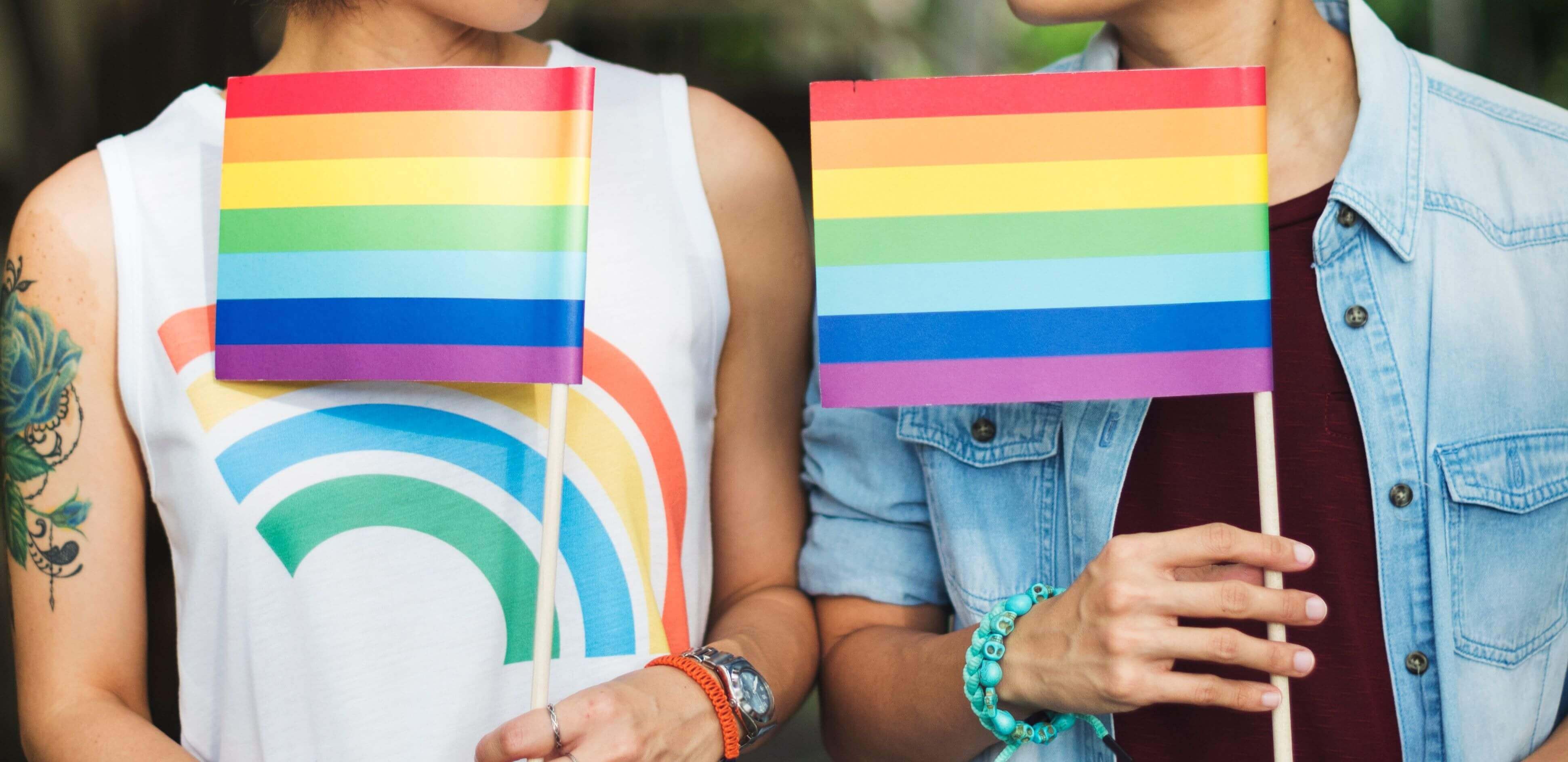 dia internacional contra a homofobia: duas pessoas exibindo uma bandeirinha com as cores LGBTQI+