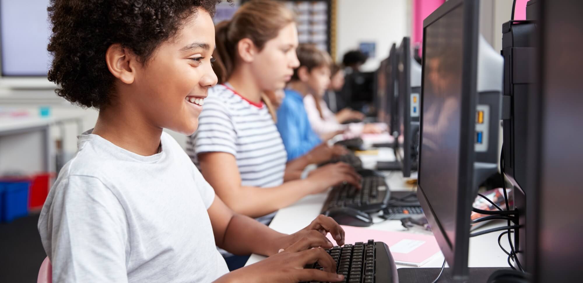 Enem Seriado: fotografia de uma sala de aula com foco em uma estudante utilizando o computador.