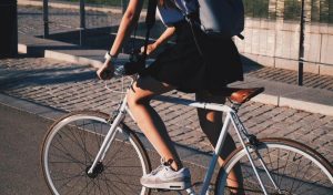 Os desafios da mobilidade urbana de baixo impacto ambiental: imagem de uma garota andando de bicicleta na cidade