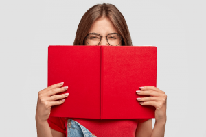 Como funciona a nota de corte do Sisu: imagem de uma menina rindo e segurando um caderno na frente do rosto