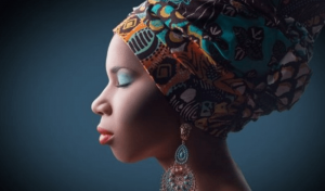 Discussão acerca da apropriação cultural: moça negra com um turbante na cabeça e com os olhos fechados.