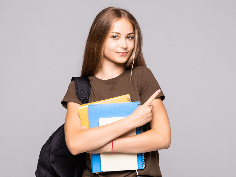 Como escrever melhor: imagem de uma menina segurando alguns cadernos
