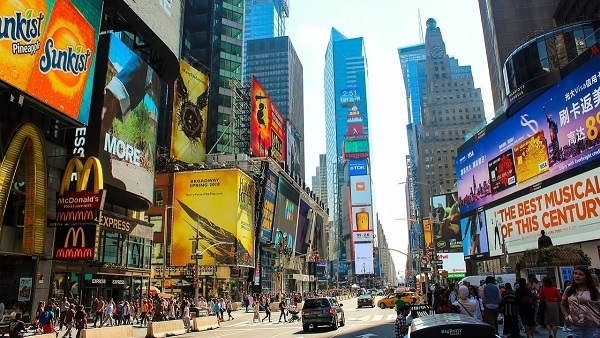 avenida times square em nova york repleta de pessoas e propagandas de diversas marcas, exemplo simbólico de cultura de massa