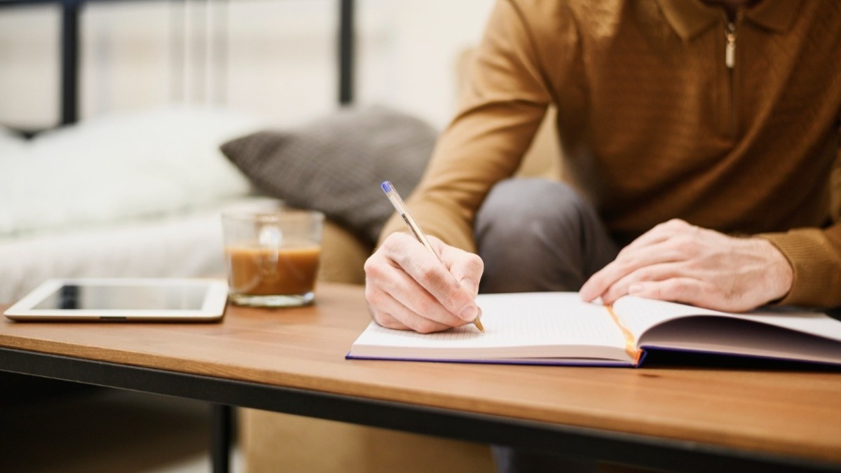 homem escrevendo em um caderno, resenha crítica